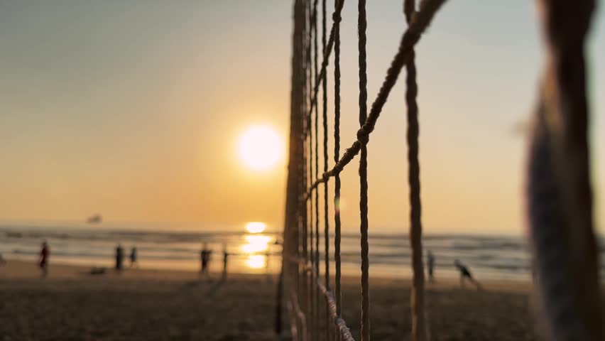 Cinematic Close up Motion through Beach Volleyball Net rope in foreground at sunset