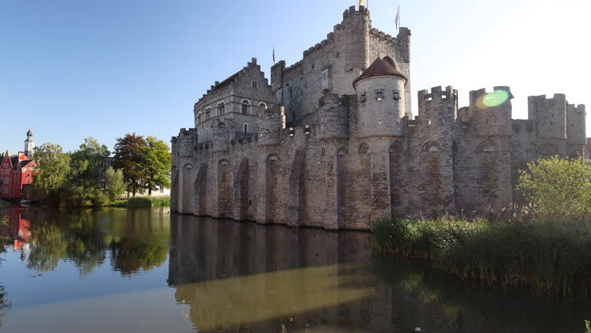 Gravensteen, a medieval castle in the city of Ghent in Belgium, Europe. Medieval Stone Fortress Reflected in Calm River Water on a Clear Sunny Day, Evoking European History
