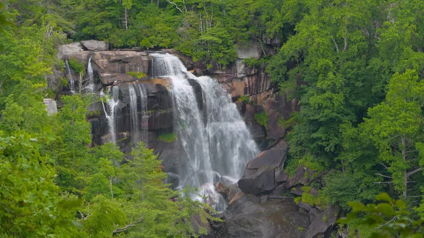 Stunning slow-motion 4K footage of Whitewater Falls cascading down rugged rocky cliffs in Cashiers, North Carolina, showcasing the power of rushing water and the breathtaking beauty of the Appalachian Mountains.
