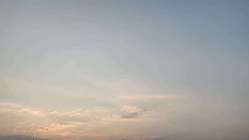 A small propeller plane traverses a vast orange and blue sunset sky with wispy clouds during golden hour. A peaceful and serene atmosphere at dusk.