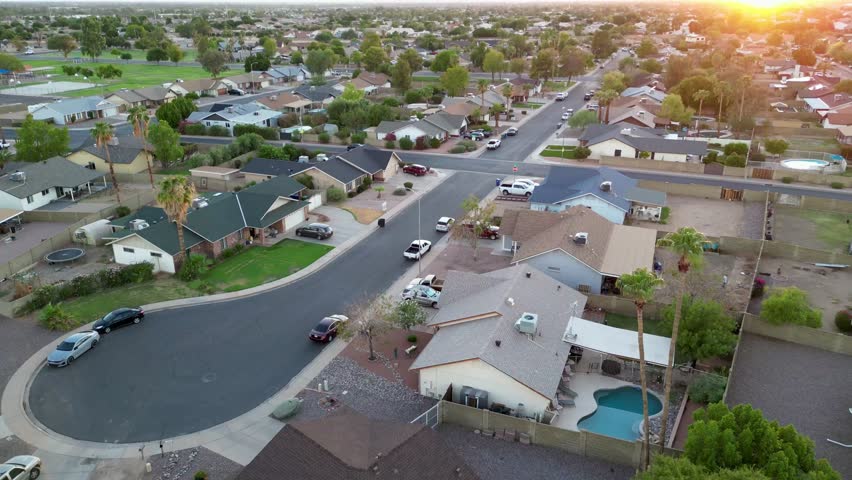 An aerial sunset view of residential neighborhood in Phoenix, Arizona, USA, with houses and swimming pools