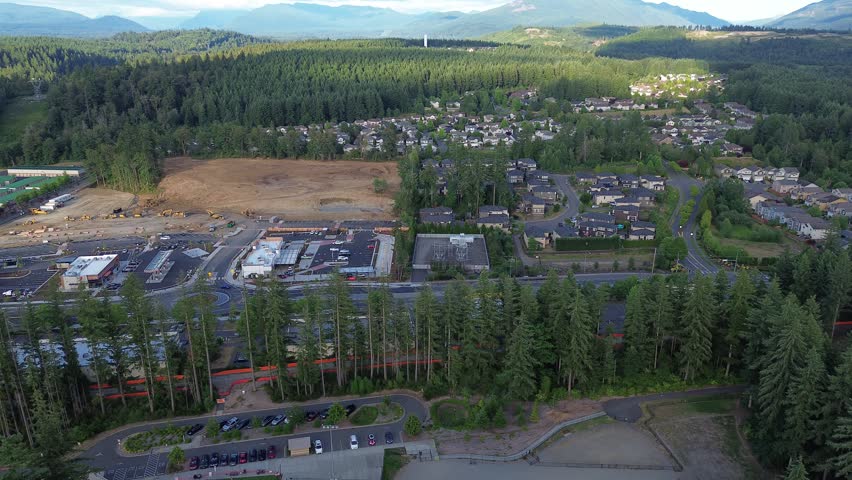 Major transit corridors intersect near ongoing commercial construction projects at Maple Valley Black Diamond Road, suburb Seattle, WA. Industrial site activity contrast against surrounding mature. US