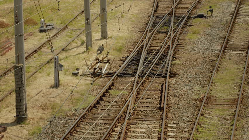 The image shows electric wires and current dividers positioned over railway tracks in an industrial area. The setup is important for power distribution along the railway.