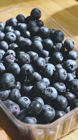 Fresh ripe blueberries in a box on a wooden table.
