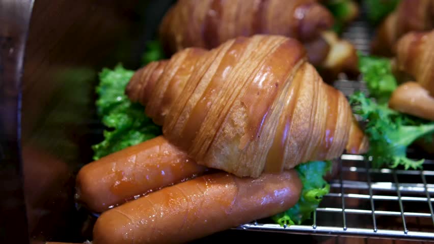 preparing a croissant sandwich. Fast breakfast. Take bacon and put it on a bun.