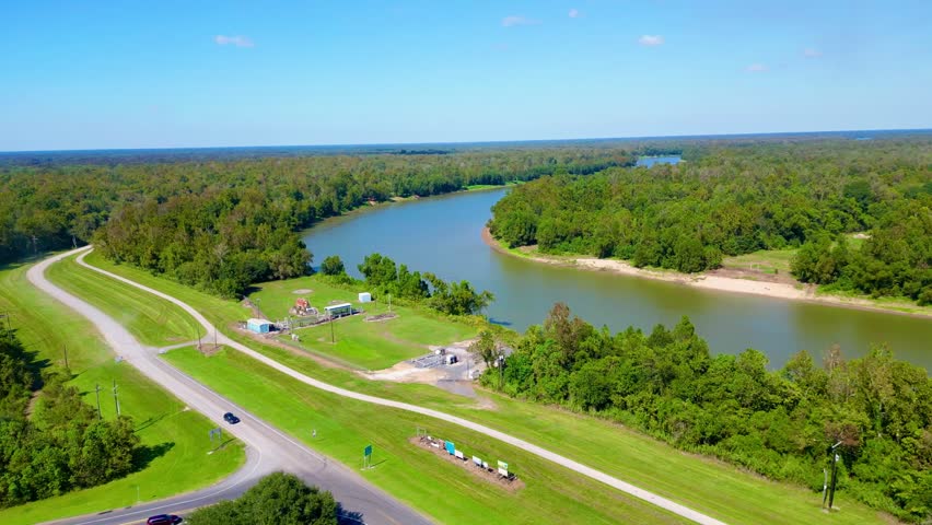 A drone shot of the Atchafalaya River cutting through a dense forest with a road, in Louisiana