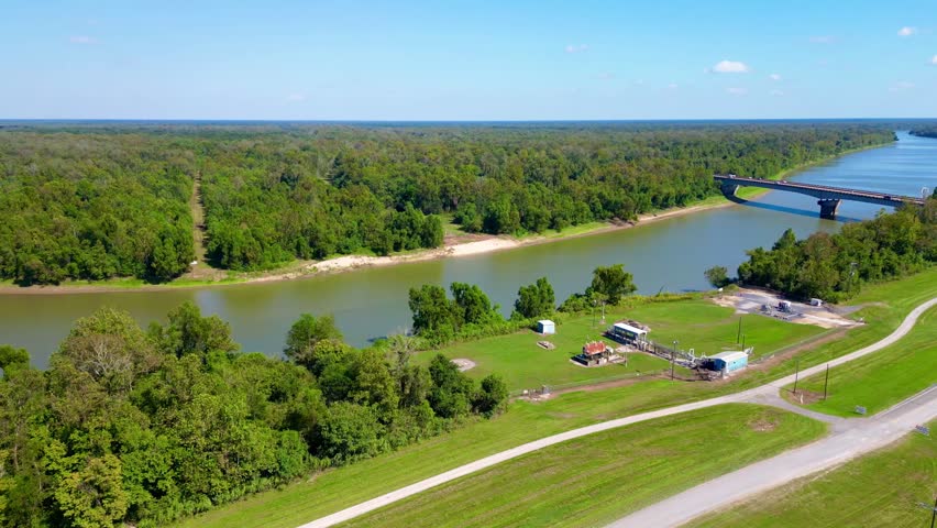 An aerial view of the Atchafalaya River in Louisiana, flowing through a green forest with a bridge