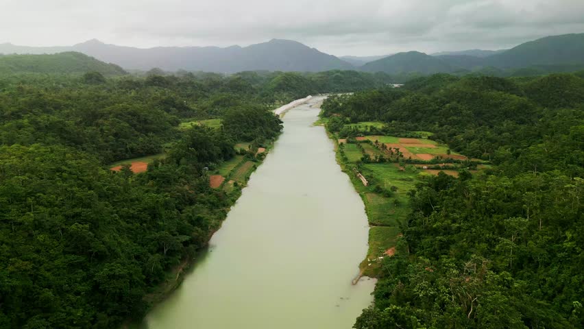 Panoramic aerial view of wide river framed by lush forest, farmlands, and mountain ranges - Pajo, Virac, Catanduanes, Philippines