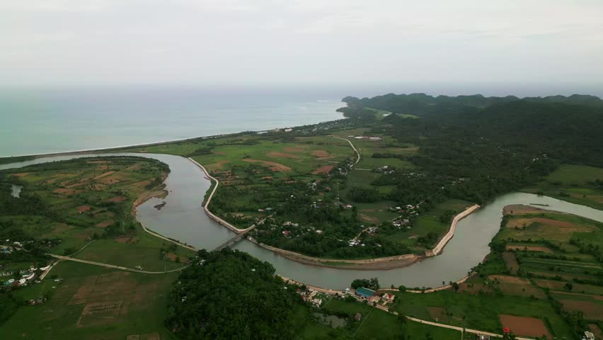 Panoramic aerial overview of Pajo River winding through tropical farmlands, rural villages, and coastal hills in Catanduanes, Philippines