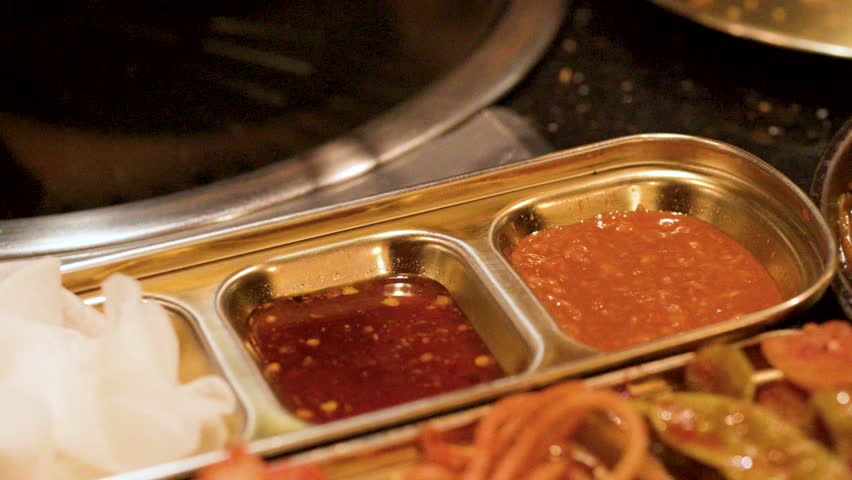 Close-up shot of crispy fried shrimp dipped into red sauce at a Korean barbecue restaurant.