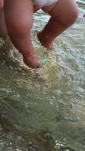 Dangling baby feet in water. Baby exploring water through sensory play.