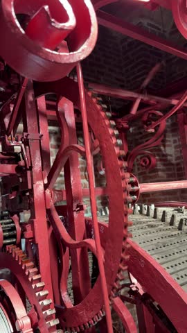 Antique ratchet mechanism operating inside a historic mechanical clockwork system. Close-up of toothed wheel, precision metal engineering and moving mechanical components demonstrating traditional clock technology, vintage industrial craftsmanship and historical engineering.