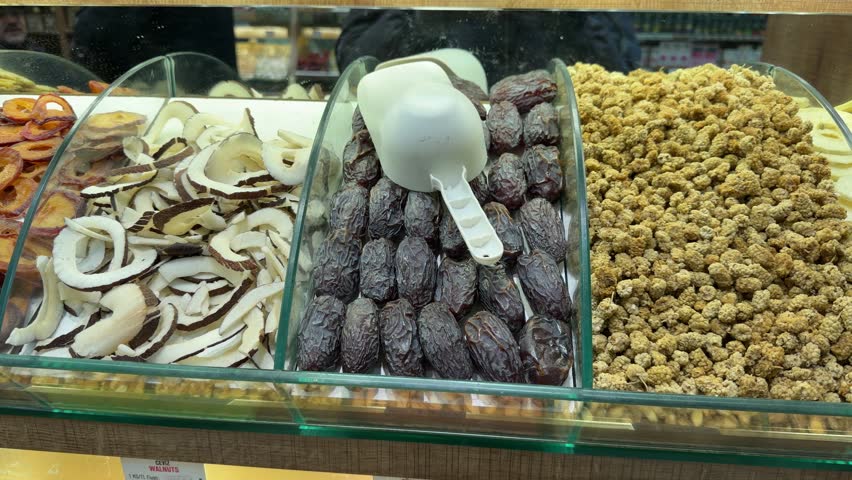 Close-up shot capturing the vibrant display of organic dried fruit, coconut chips, and pitted dates at a traditional bustling spice market in Istanbul, Turkey.