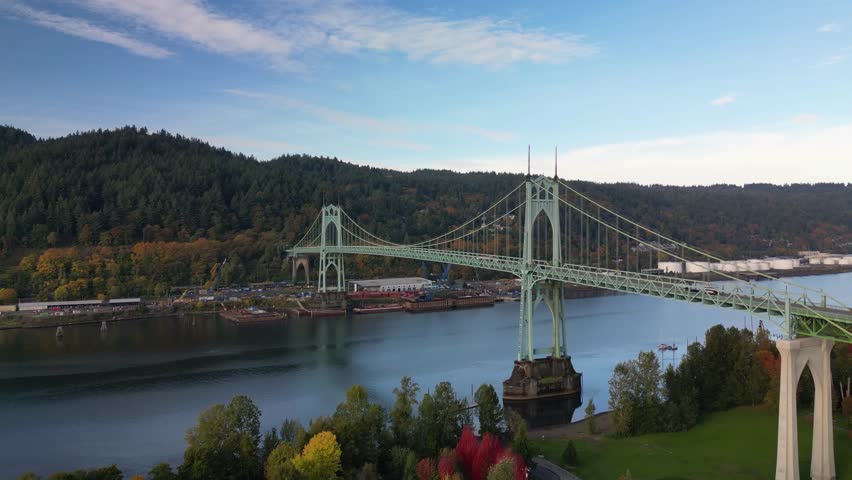 An aerial view of St. Johns Bridge spanning the Willamette River in Portland, Oregon, USA surrounded by autumn trees and forested hills