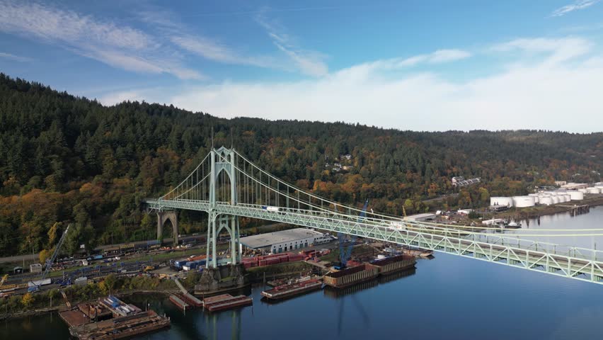 A drone footage of St. Johns Bridge spanning the Willamette River in Oregon, USA surrounded by autumn trees and forested hills
