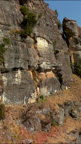 Cinematic drone footage flying past a rocky foreground to reveal the dramatic peaks of the Drakensberg Mountains in South Africa. Scenic aerial landscape showcasing the rugged beauty of one of Africa