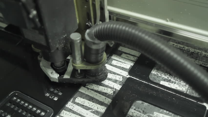 Camera on jib moves around a CNC machine as it cuts out industrial parts for