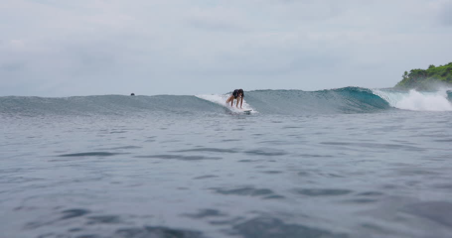 Surfer riding on surfboard during surfing. Female surfer rides on ocean wave