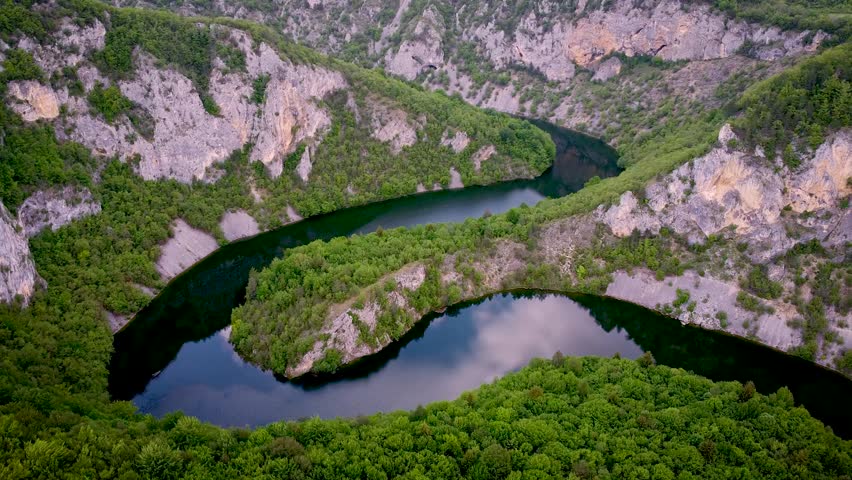 Stunning aerial footage showing the breathtaking horseshoe bend of the Uvac River. The calm water meanders through a deep canyon of rocky cliffs