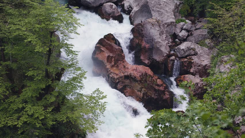 Beautiful mountain stream with powerful whitewater rapids crashing against rocks. Wild river cascading through a pristine forest