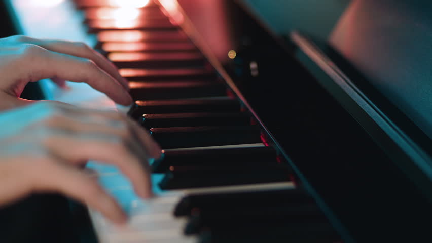 Pianist playing classical music on grand piano keys. Musician hands performing melody during performance. Artistic practice of musical instrument in dark studio.