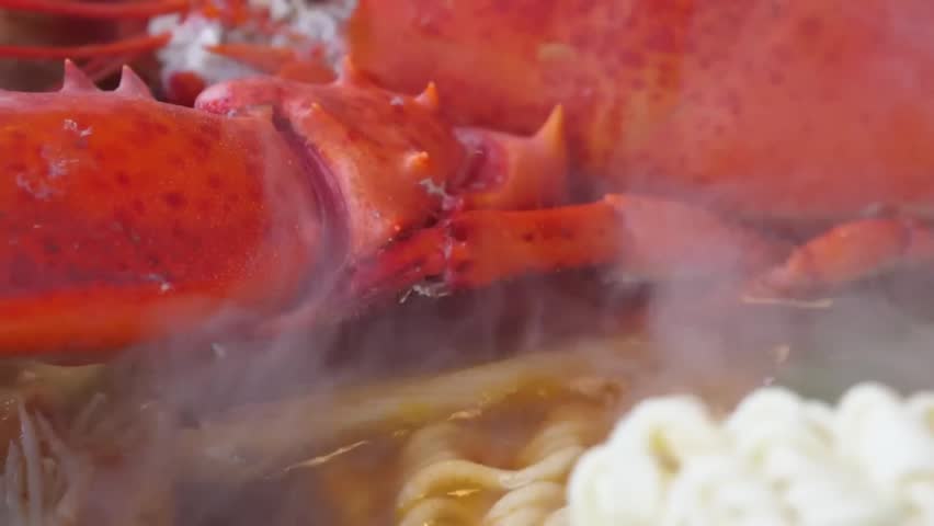 A mouthwatering macro shot of a freshly cooked red lobster claw and body steaming over a savory bed of noodles, capturing the hot vapor and vibrant textures of a gourmet seafood dish.