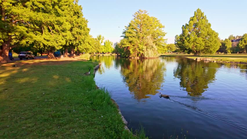 Serene canal reflects golden dusk light beneath lush willow trees at Ann Morrison Park in Boise Idaho