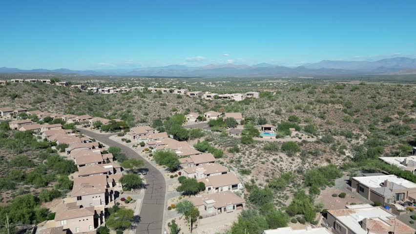 An aerial view of Fountain Hills, Arizona, with desert-style homes along winding streets surrounded by Sonoran vegetation and distant mountain ranges