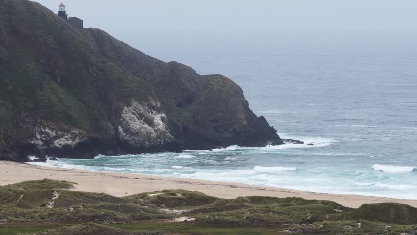 Scenic View of Point Sur Lighthouse atop Coastal Cliff and Sandy Beach in Big Sur, California