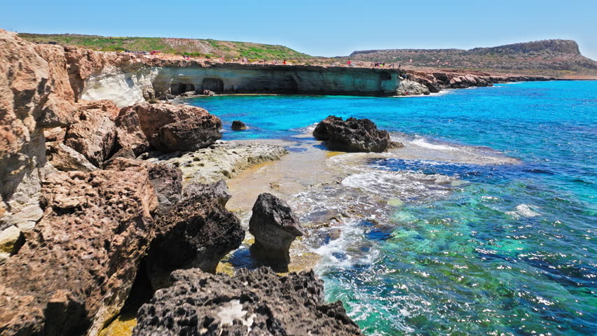 Aerial view of Cape Cavo Greco sea caves in Cyprus. Rocky limestone cliffs, turquoise water and rugged coastal formations create a dramatic Mediterranean landscape.