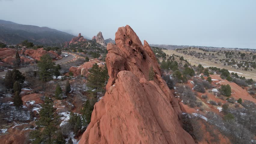 A drone view of massive red rock walls rising from snowy foothills at Garden of the Gods in Colorado Springs, Colorado, USA