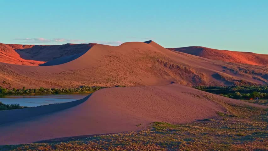 Scenic view of golden sand dune curves at sunset in Bruneau Dunes State Park, Idaho, showing rippled desert formations and warm evening light