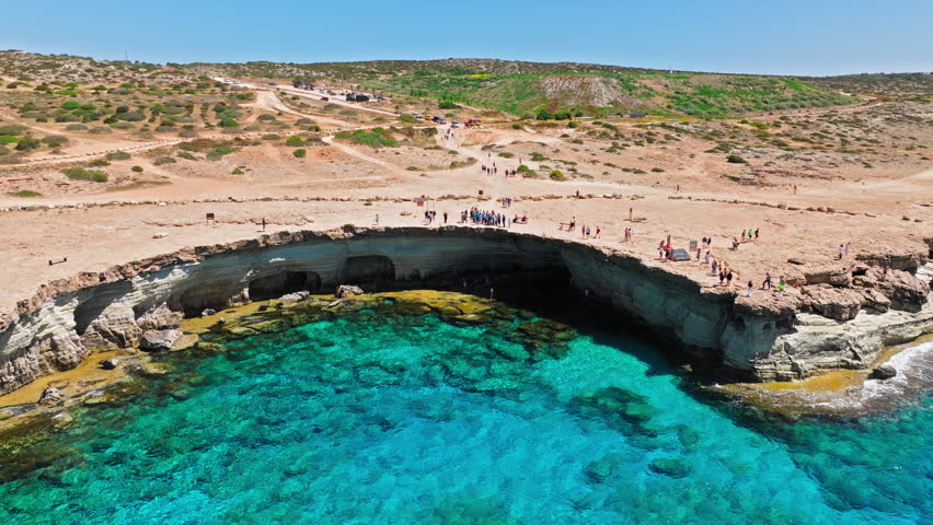 Drone view of Cape Cavo Greco sea caves in Cyprus. Rocky limestone arch, turquoise water and rugged shoreline create an iconic Mediterranean landmark.