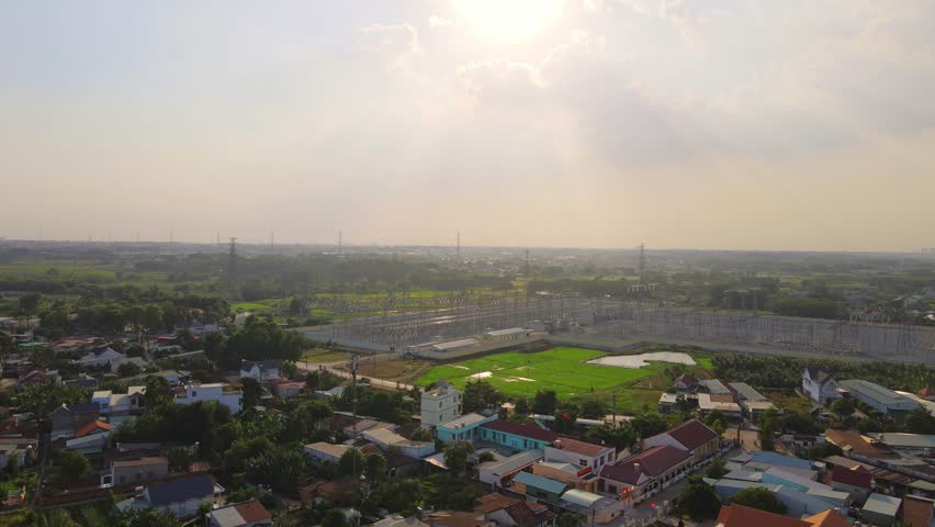 An erial view of a rural Vietnamese town with sunlit fields and scattered homes surrounded by green vegetation at dusk