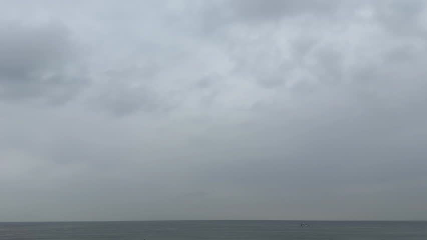 Boat Sailing Along the Horizon Under Heavy Clouds