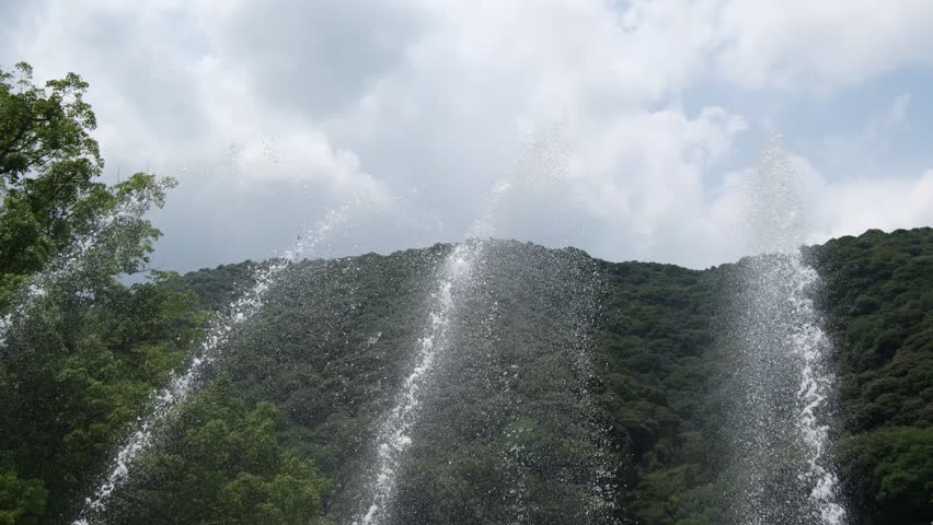 Arcing Fountain Water Jets Spraying Outdoors Against Mountain Scenery