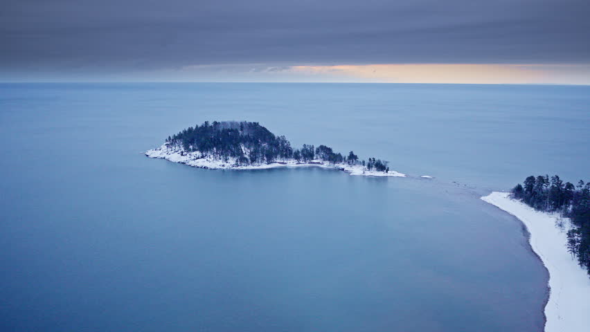 Sweeping drone shot of the frozen winter terrain bordering Lake Superior in Northern Michigan.