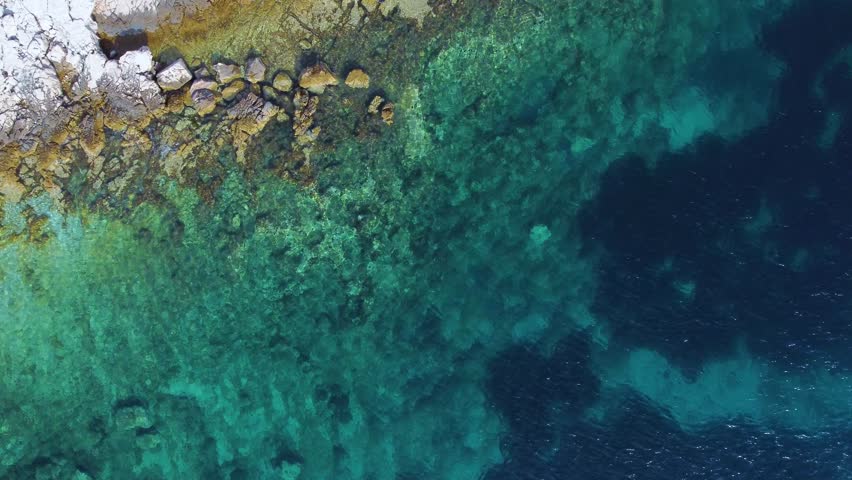 Aerial top down view of the stunning rocky coast of hvar island in croatia. Clear turquoise water gently washes over the seabed