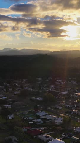 Wide aerial shot of a residential neighborhood and distant mountains during golden hour in Australia.