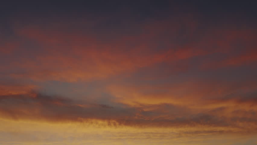 Slow-moving layers of pink and orange clouds fill the horizon against a deepening dusk sky, useful as atmospheric background or contemplative transition shot, Manitowoc, Wisconsin