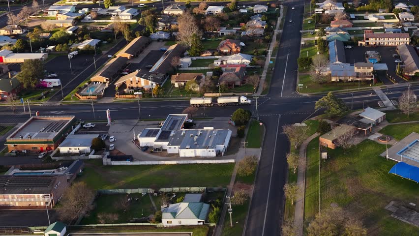 High-angle drone shot of a white truck navigating a residential intersection in Coonabarabran, Australia.