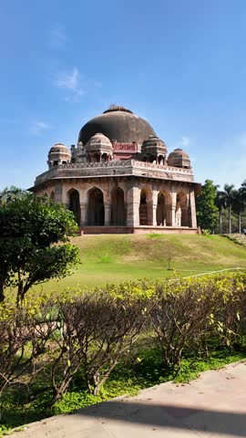 A historic stone tomb set in a lush city park.