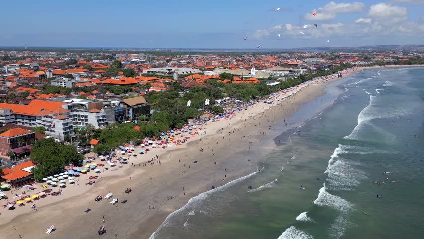 Aerial view of Kuta Beach during the traditional Bali Kite Festival in Bali, Indonesia. Colorful kites fill the sky above the famous coastline, sandy beach, and Indian Ocean.