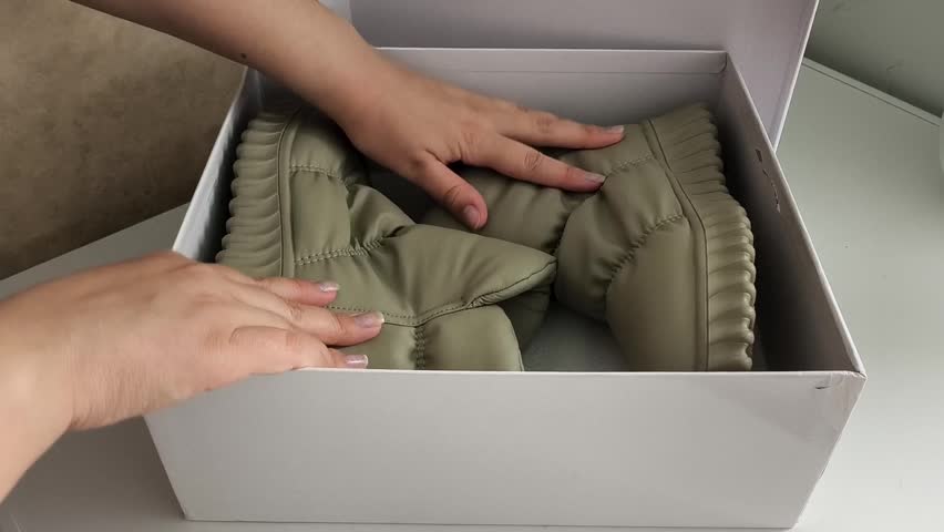 Woman packing footwear into box for storage, shoe organization, retail packaging, manufacturing and moving concept. shoe manufacturing