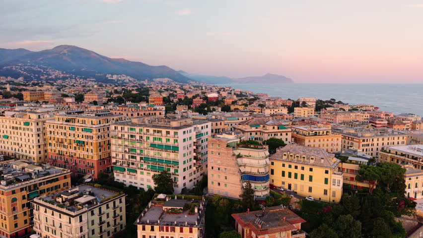 Aerial view panning over Genoa’s coastline with colorful buildings at sunset