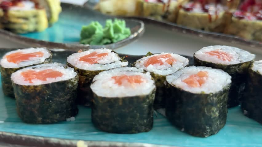 Salmon hosomaki sushi rolls wrapped in nori seaweed on black serving plate, traditional Japanese maki with rice and fresh fish ready to eat