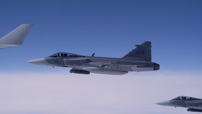 Advanced Fighter Jet Flying Alongside Support Aircraft Above Clouds During Strategic High Altitude Patrol Mission.