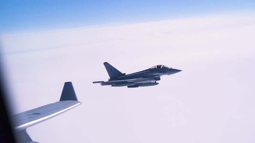 Military Fighter Jet Escorting Aircraft Above Clouds During High Altitude Flight Operations Mission.