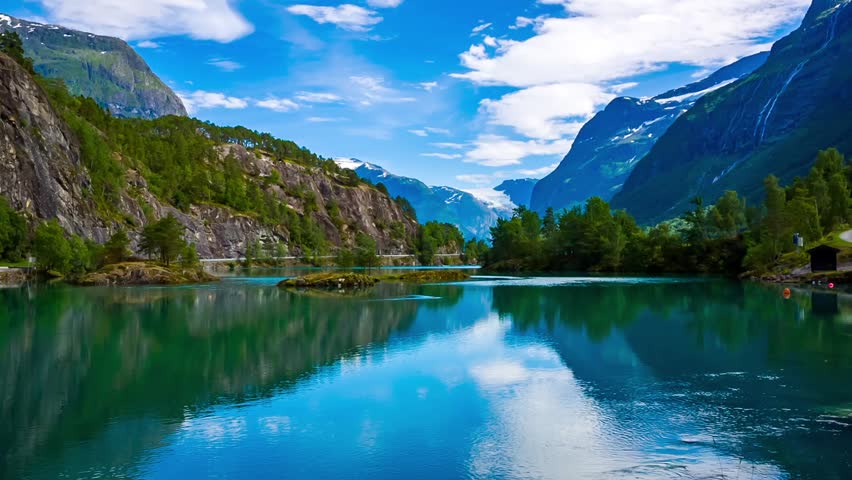 Majestic snowcapped mountains tower over a serene turquoise lake reflecting the brilliant blue sky and white clouds in a breathtaking natural landscape scene