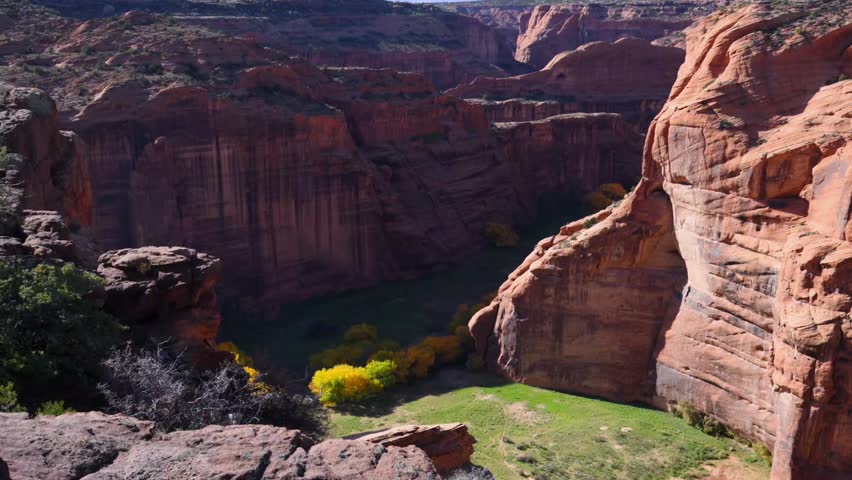 Landscape of Canyon de Chelly National Monument, located near Chinle, Arizona, USA. The principal attraction is Antelope House Overlook, which offers panoramic views of the canyon system and the archaeological ruins of Antelope House, an ancestral Puebloan cliff dwelling. The dark streaks visible on the sandstone canyon walls are known as desert varnish, a natural surface coating composed primarily of manganese and iron oxides. Navajo families continue to reside within the canyon, practicing traditional livestock husbandry and agriculture in accordance with their cultural heritage. Arizona, USA.